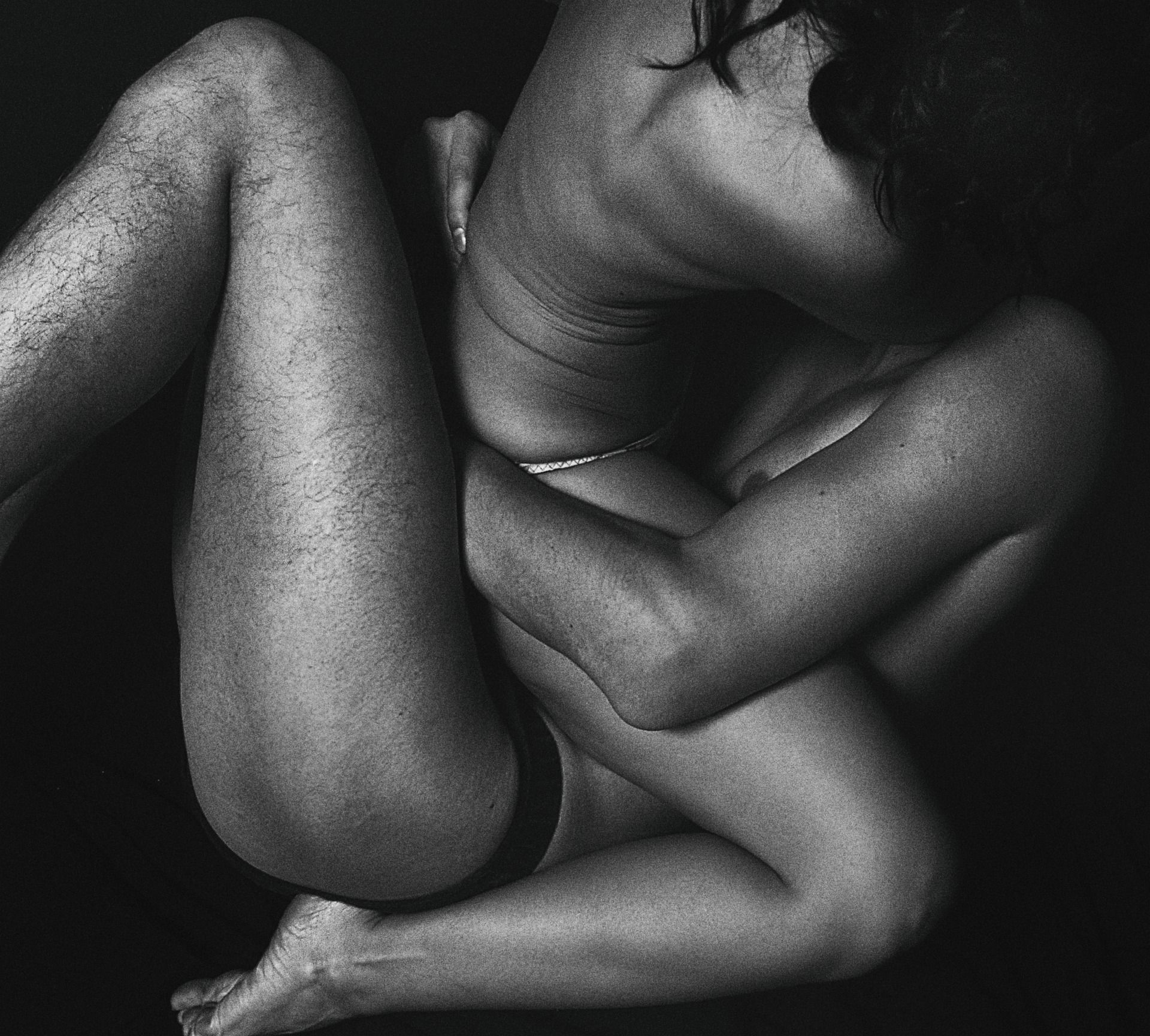 Black and white photo of a couple with legs and arms wrapped together