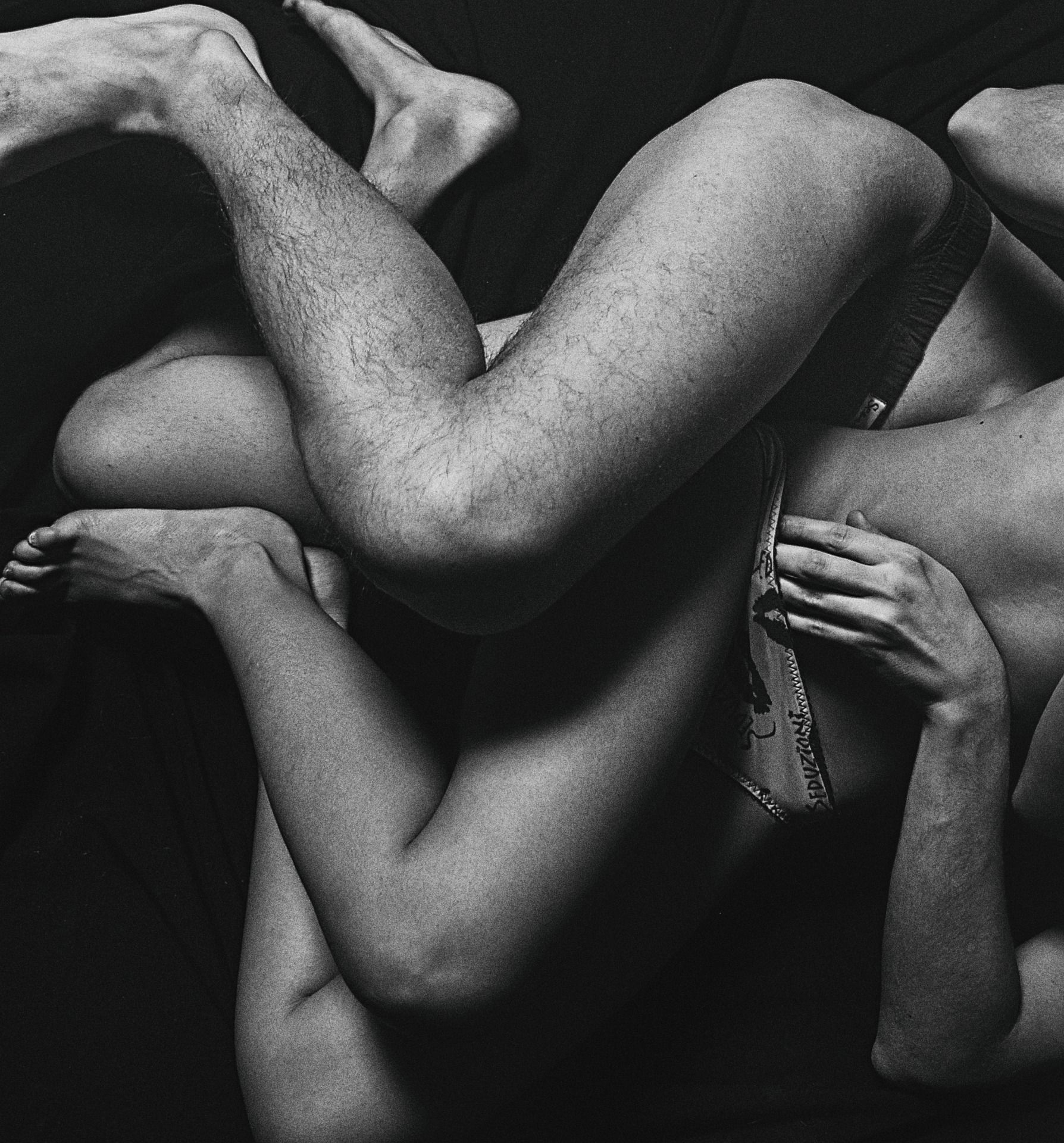 Black and white photo of a couple entwined on a bed